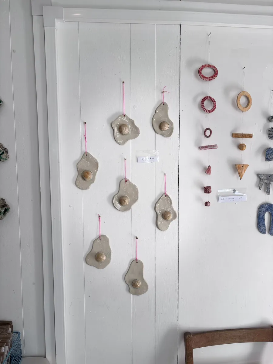 Glazed fried-egg wall hangings on pink cord, hung on a white wall