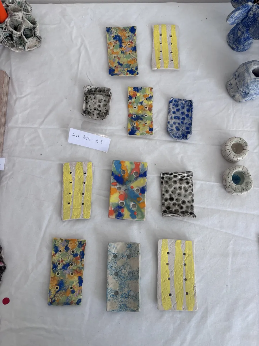 Striped, speckled and splattered soap dishes laid out on a stall