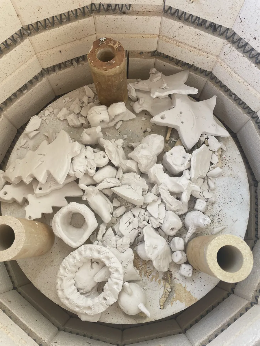 A kiln full of bisque-fired stars, trees and little pots