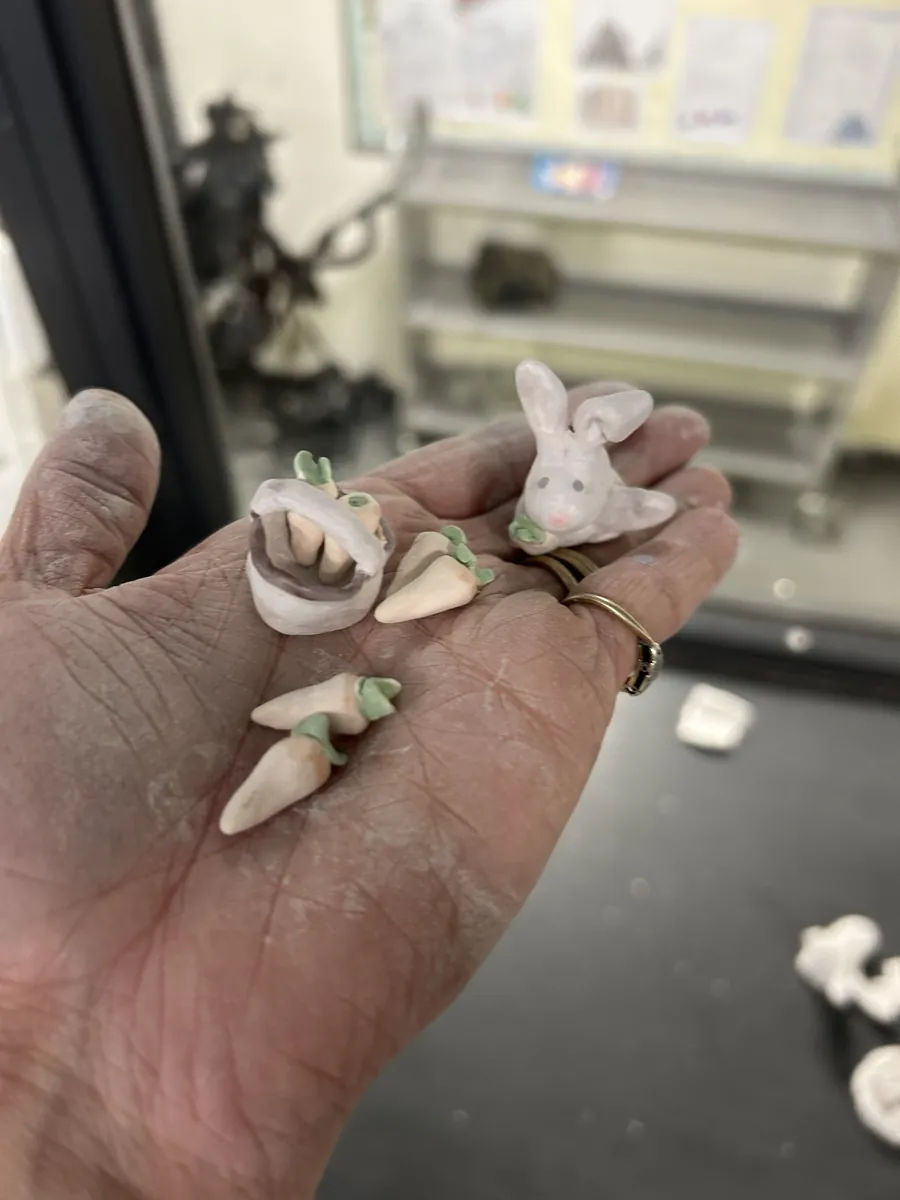 A tiny bunny, basket and carrots made at clay club, held in Gemma's hand