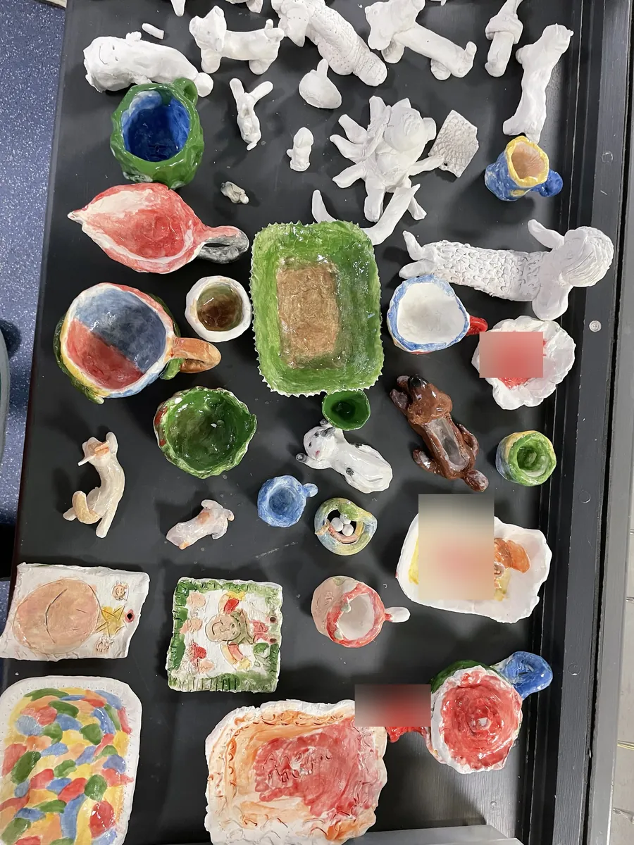 A tray of glazed cups, dishes and animals made at clay club