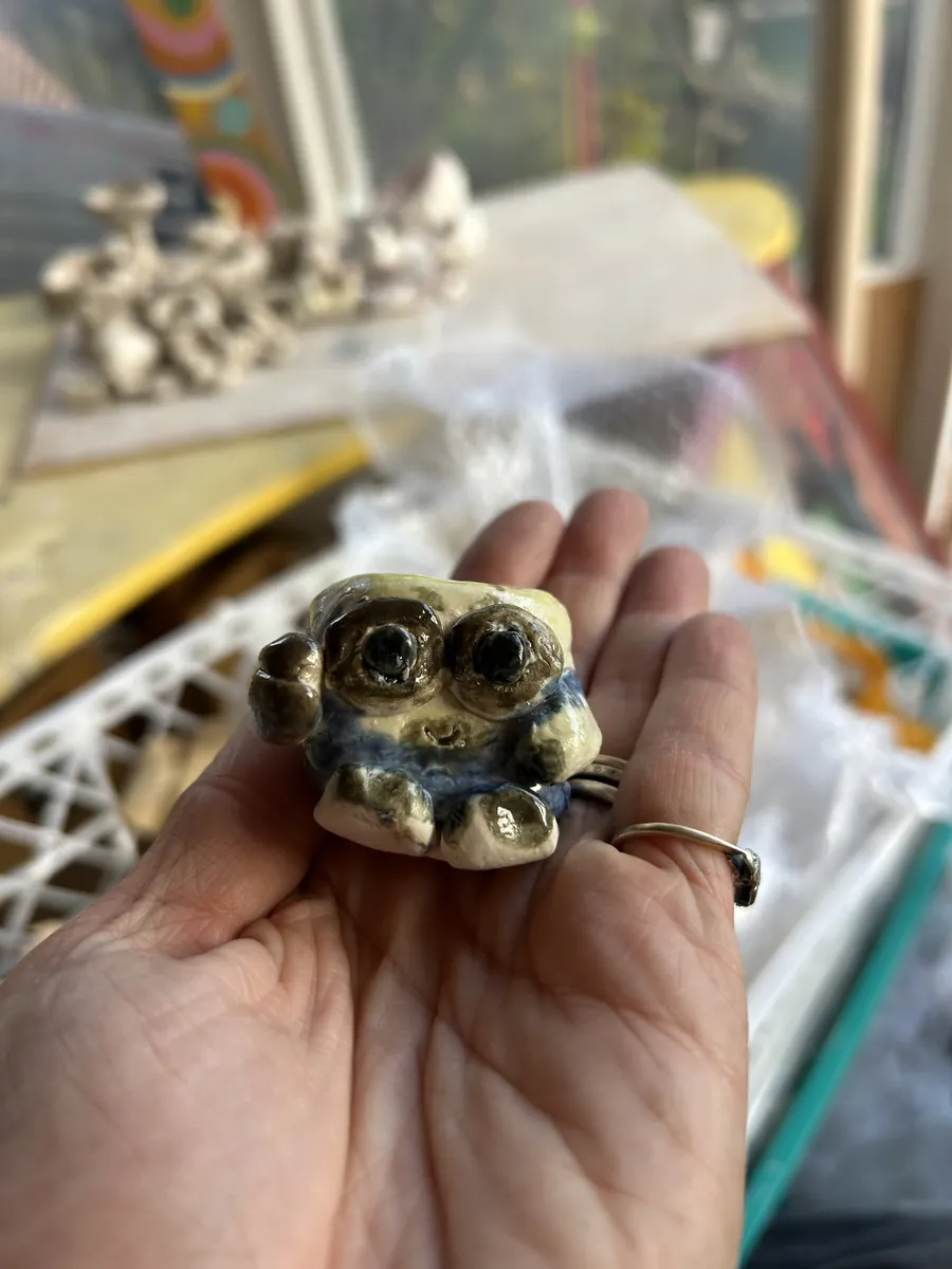 A tiny creature with big goggle eyes in the palm of a hand