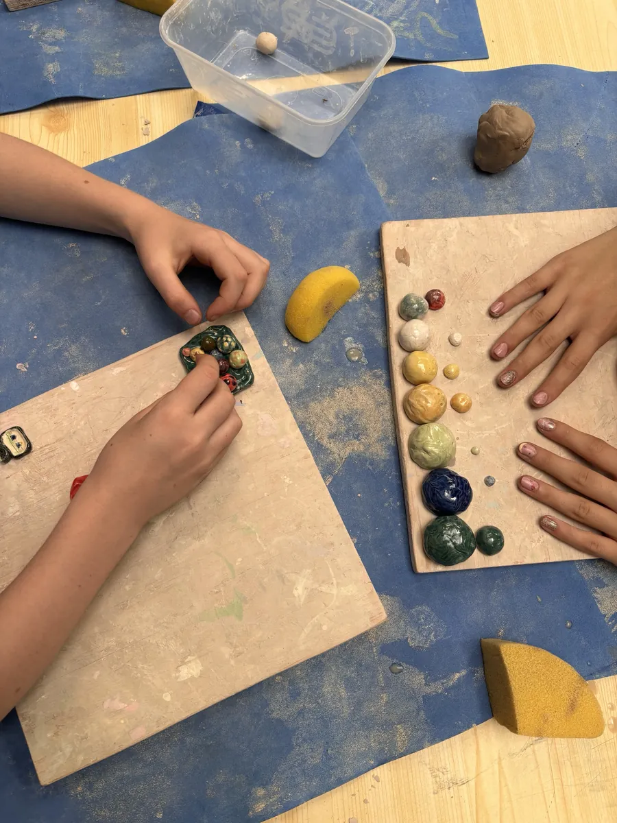 Two children arranging glazed clay balls on boards