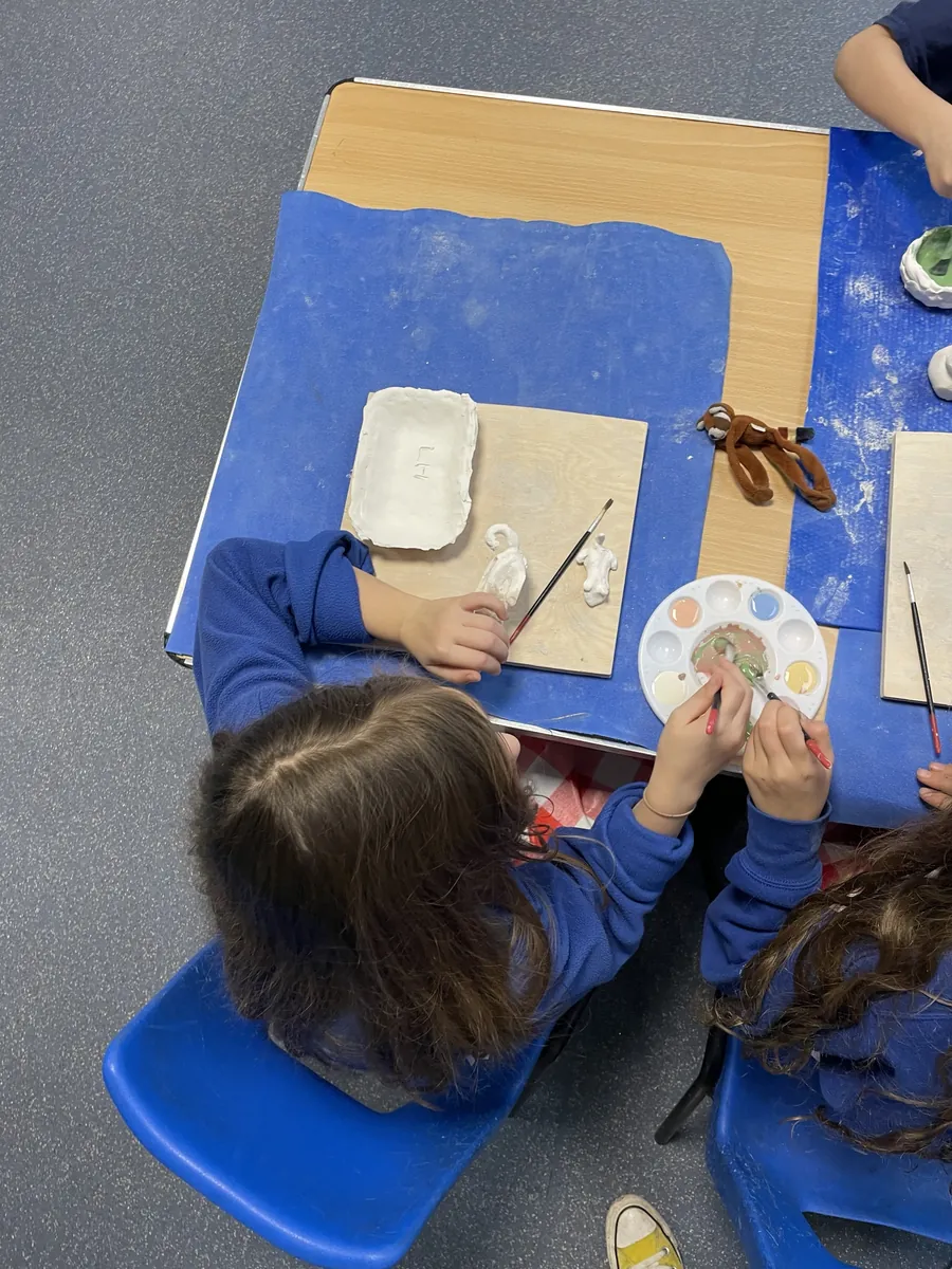 A child mixing glaze colours on a palette
