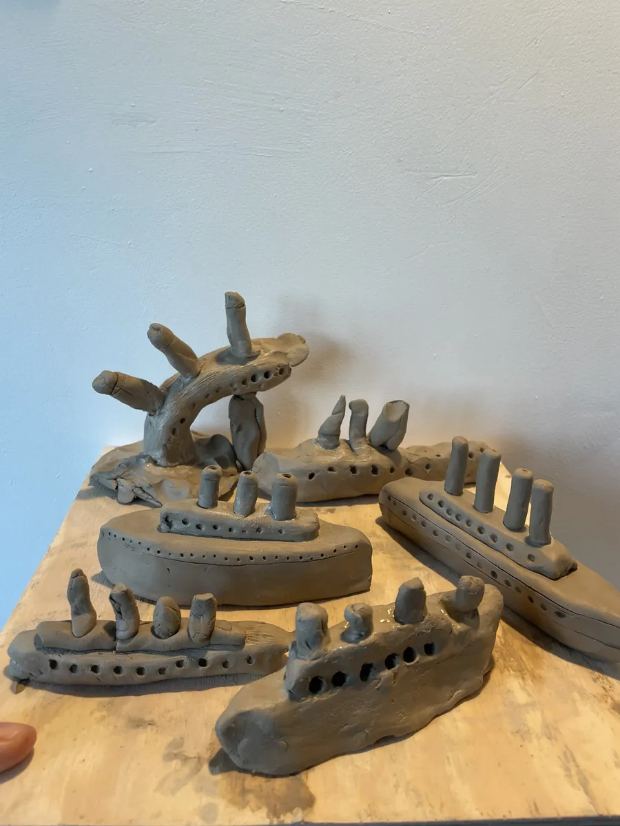 A fleet of unfired clay steamships with funnels and portholes
