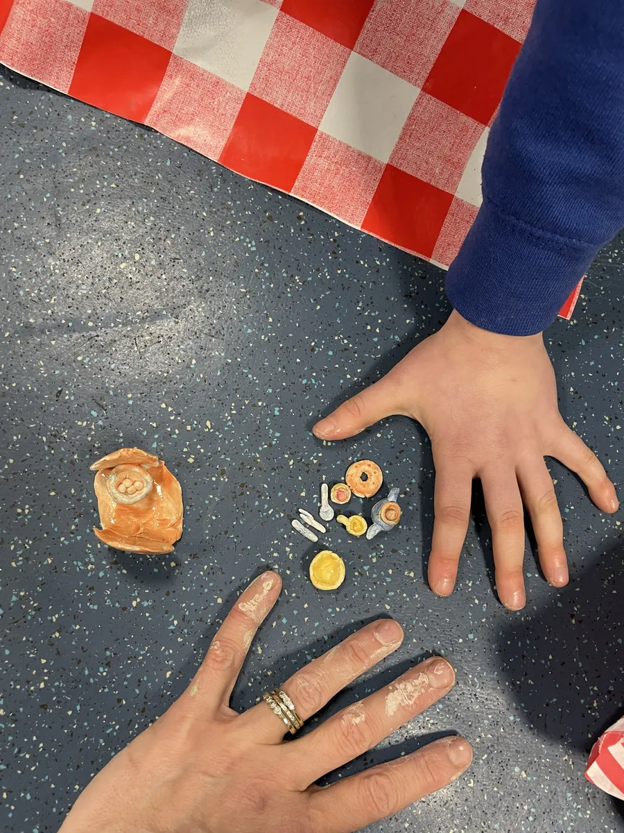 A tiny tea set and nest held between Gemma's hand and a child's