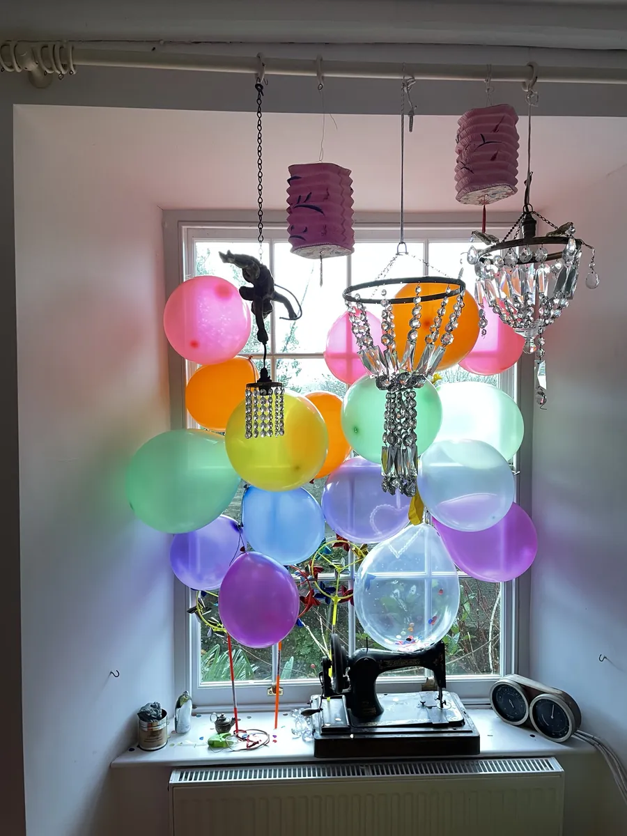 A window dressed with pastel balloons, crystal chandeliers and paper lanterns