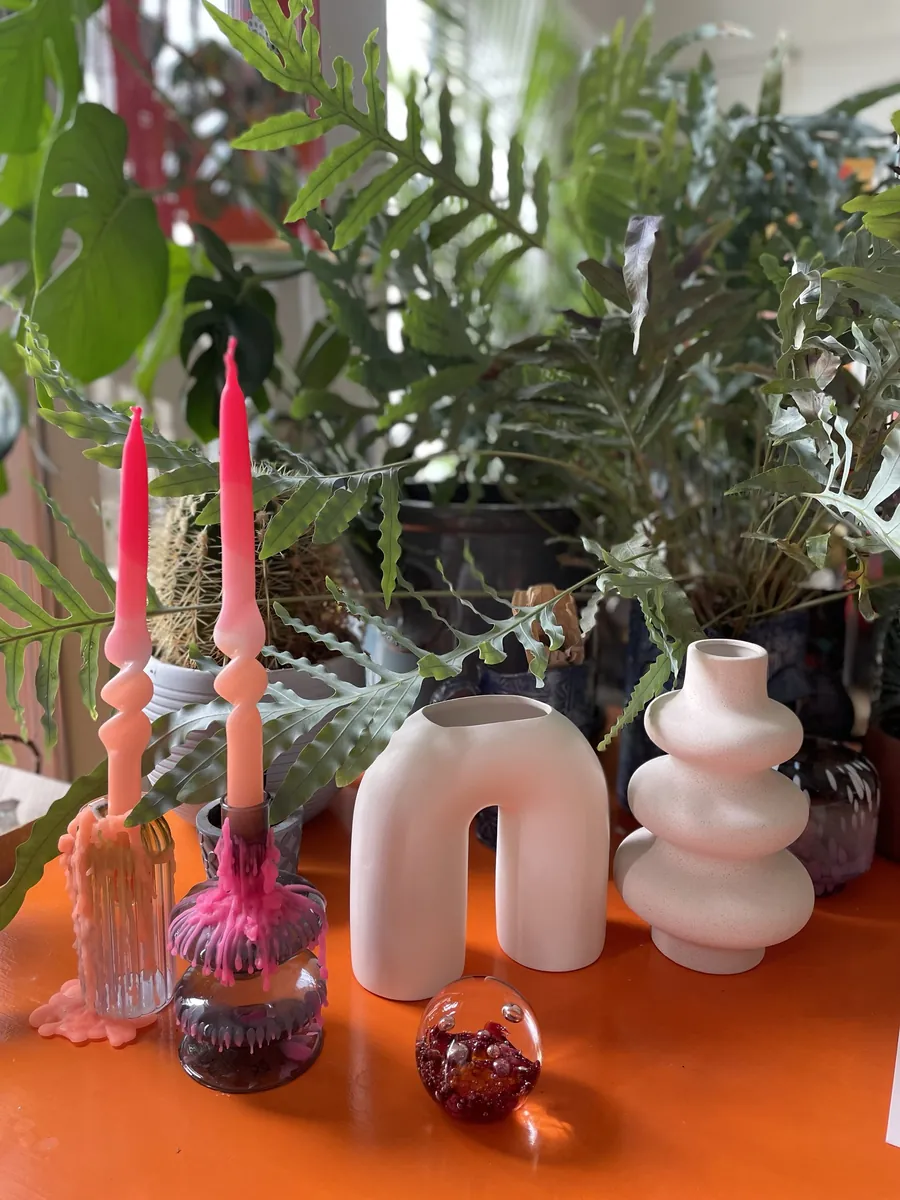 Pink dripping candles and pale sculptural vases on an orange table