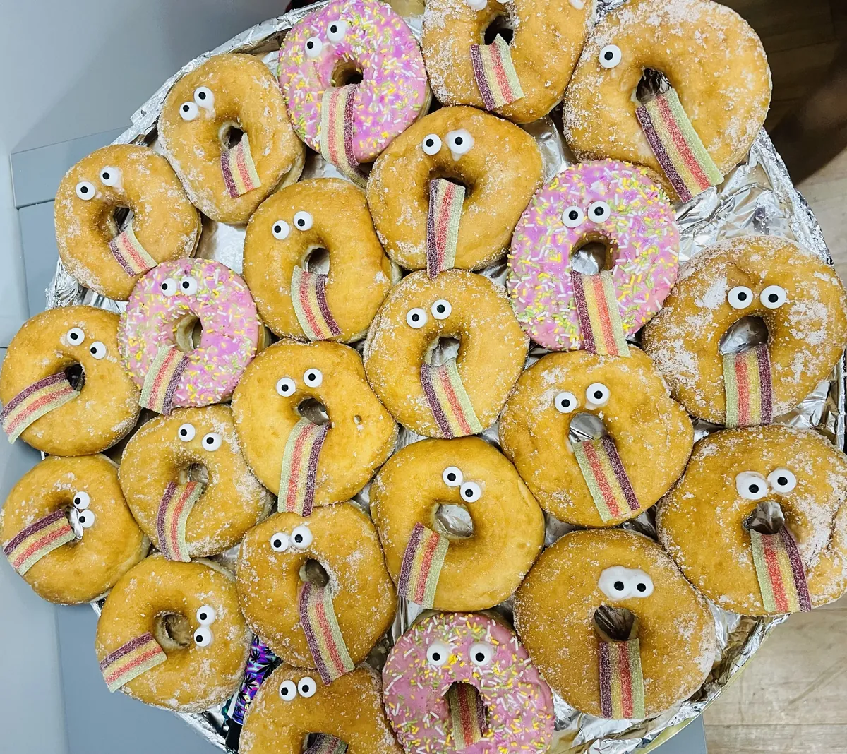 A platter of doughnuts with googly eyes and sour rainbow tongues