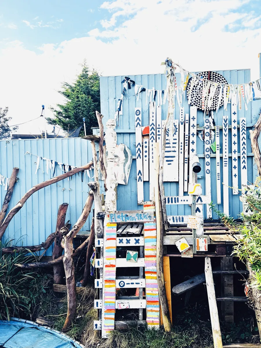 A garden platform with a striped ladder and hand-painted fence panels