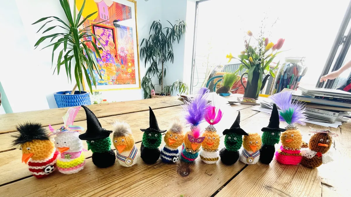 A row of knitted chick egg cosies dressed as witches, footballers and showgirls