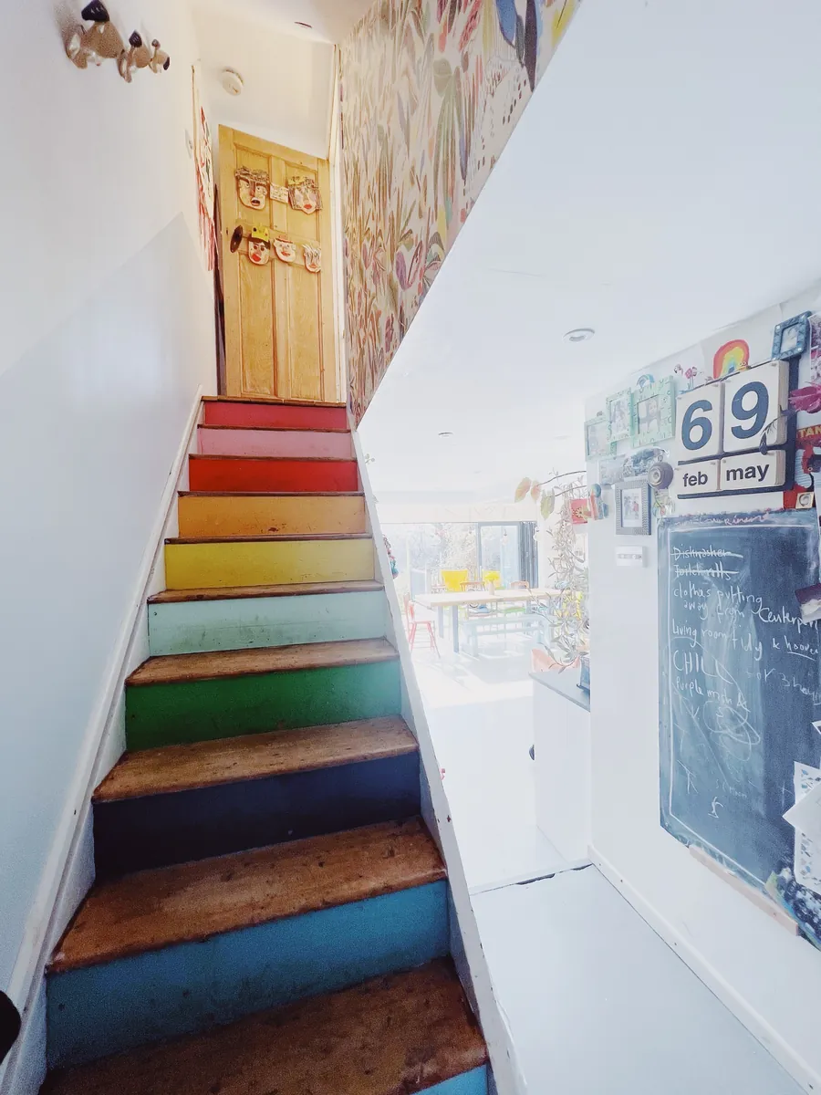 Rainbow-painted stairs below a hand-painted botanical mural