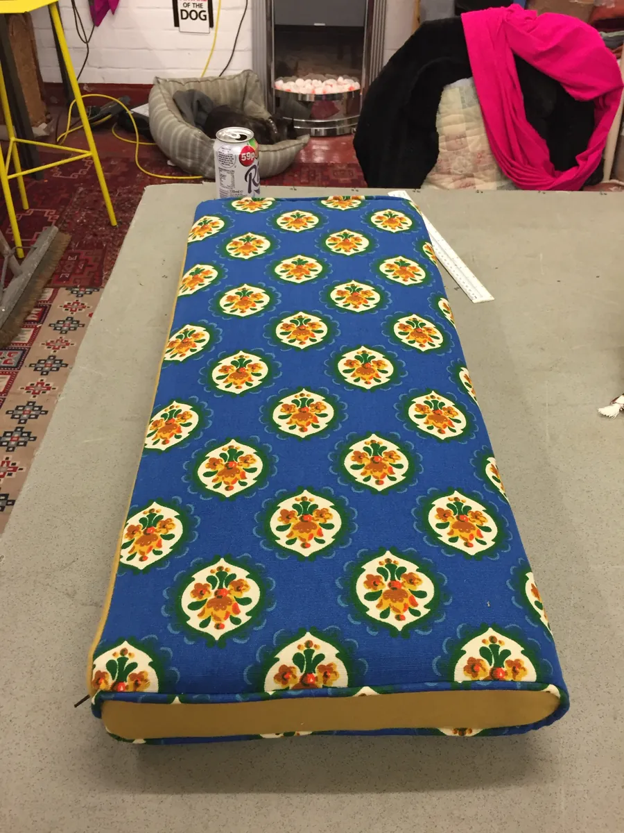 A box cushion in blue folk-floral fabric with mustard sides