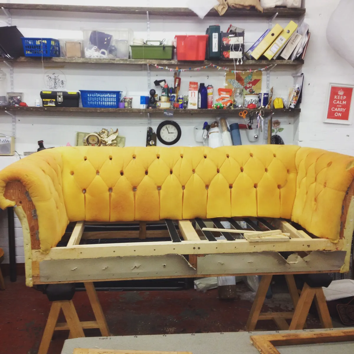 A buttoned Chesterfield back in yellow foam, stripped back to the frame on trestles