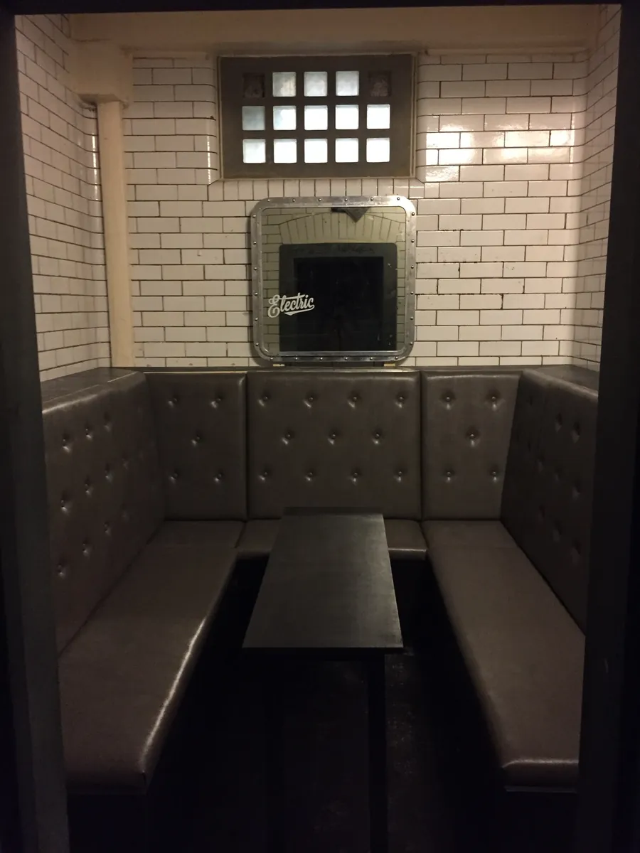 A buttoned grey booth seat in a white-tiled alcove