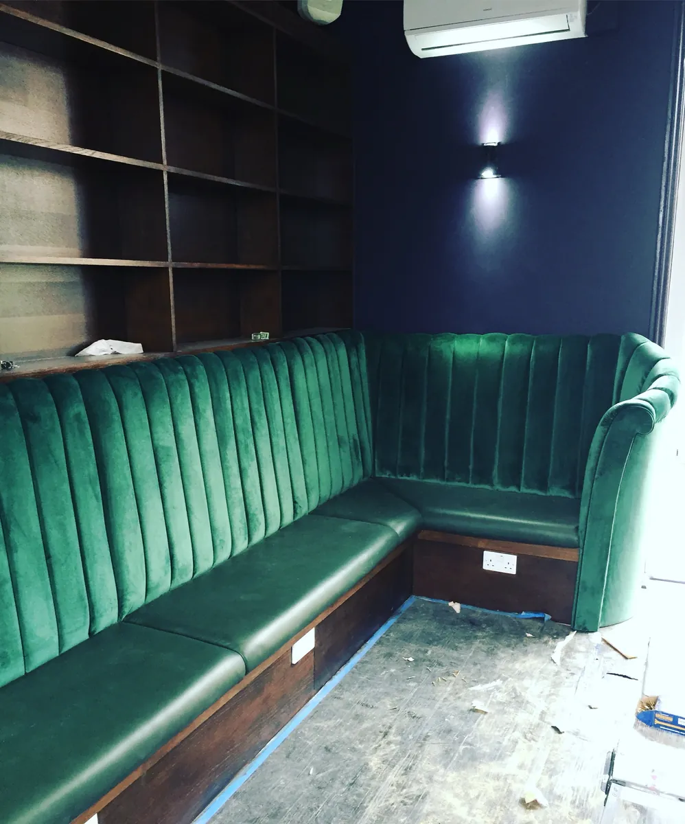 A fluted emerald velvet banquette fitted around a corner
