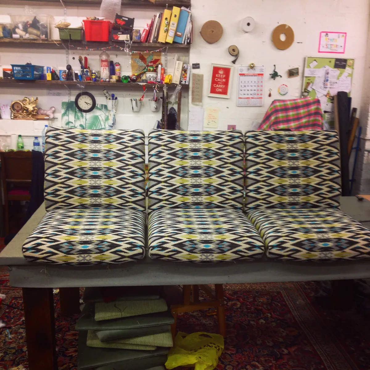 Three bench seats covered in a black, lime and turquoise kilim weave
