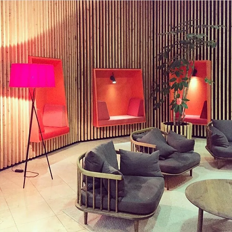 Orange upholstered seating nooks set into a slatted timber wall