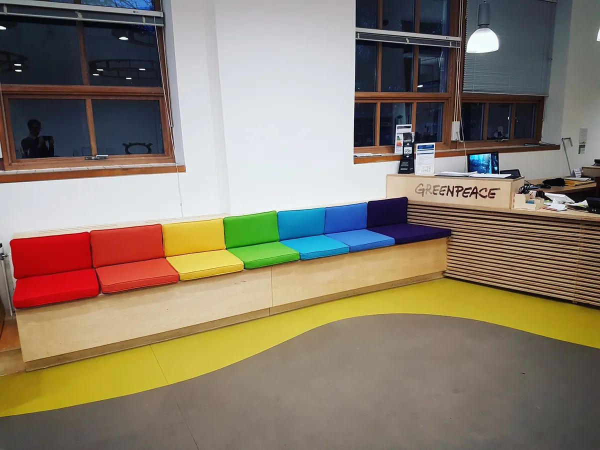 A long reception bench with seat cushions in every colour of the rainbow