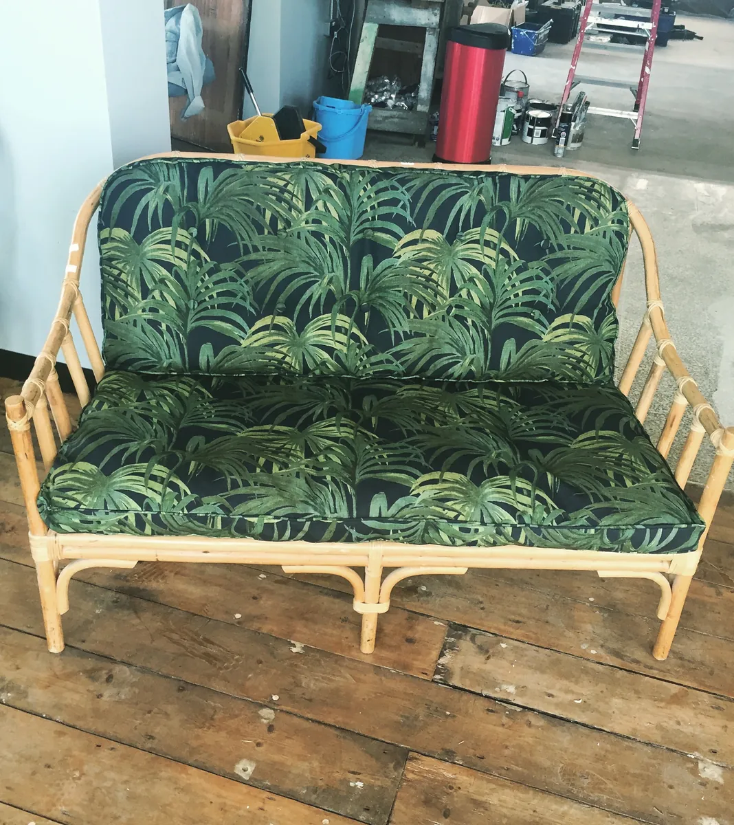 A rattan sofa with buttoned cushions in green palm print