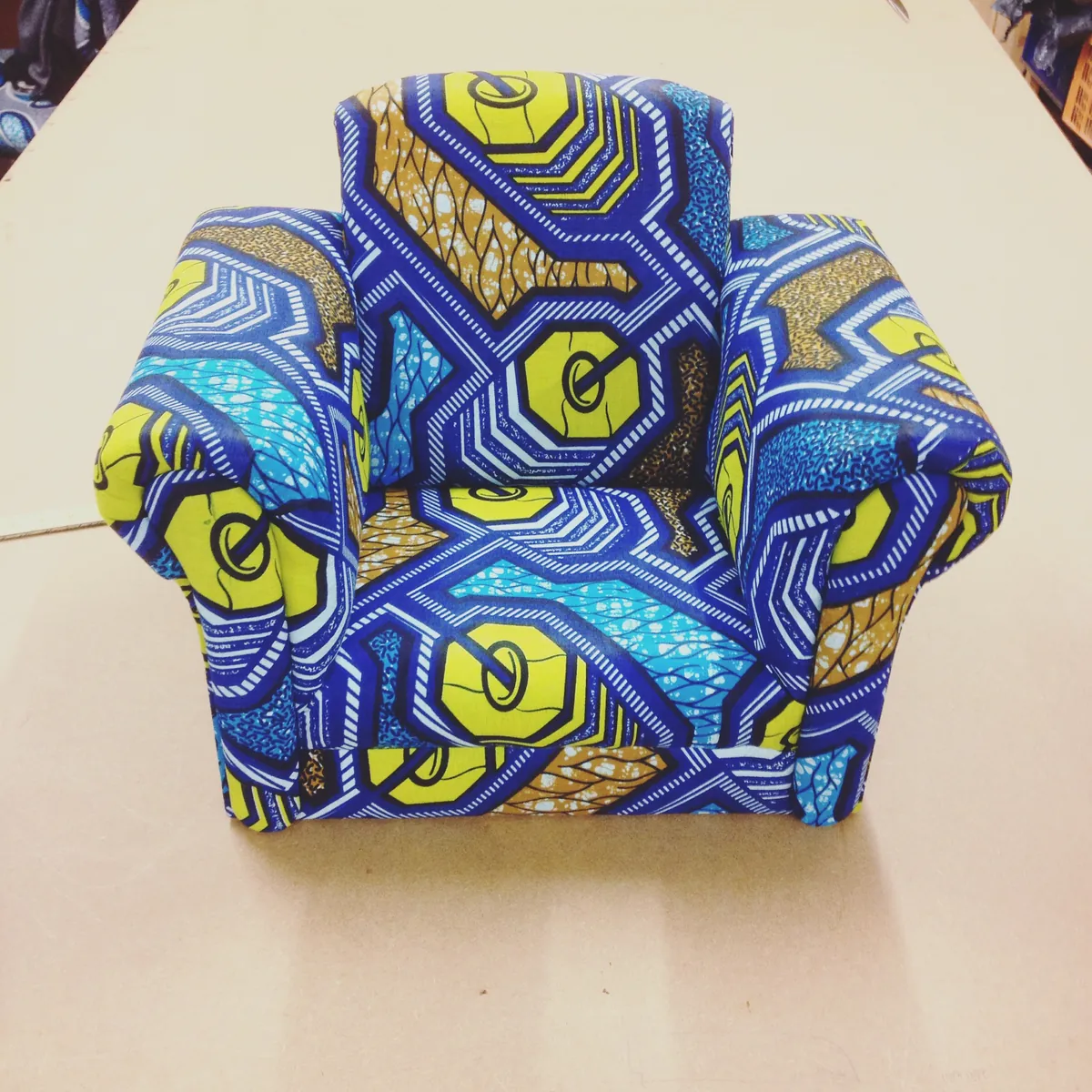 A child's armchair covered in a blue and yellow wax print