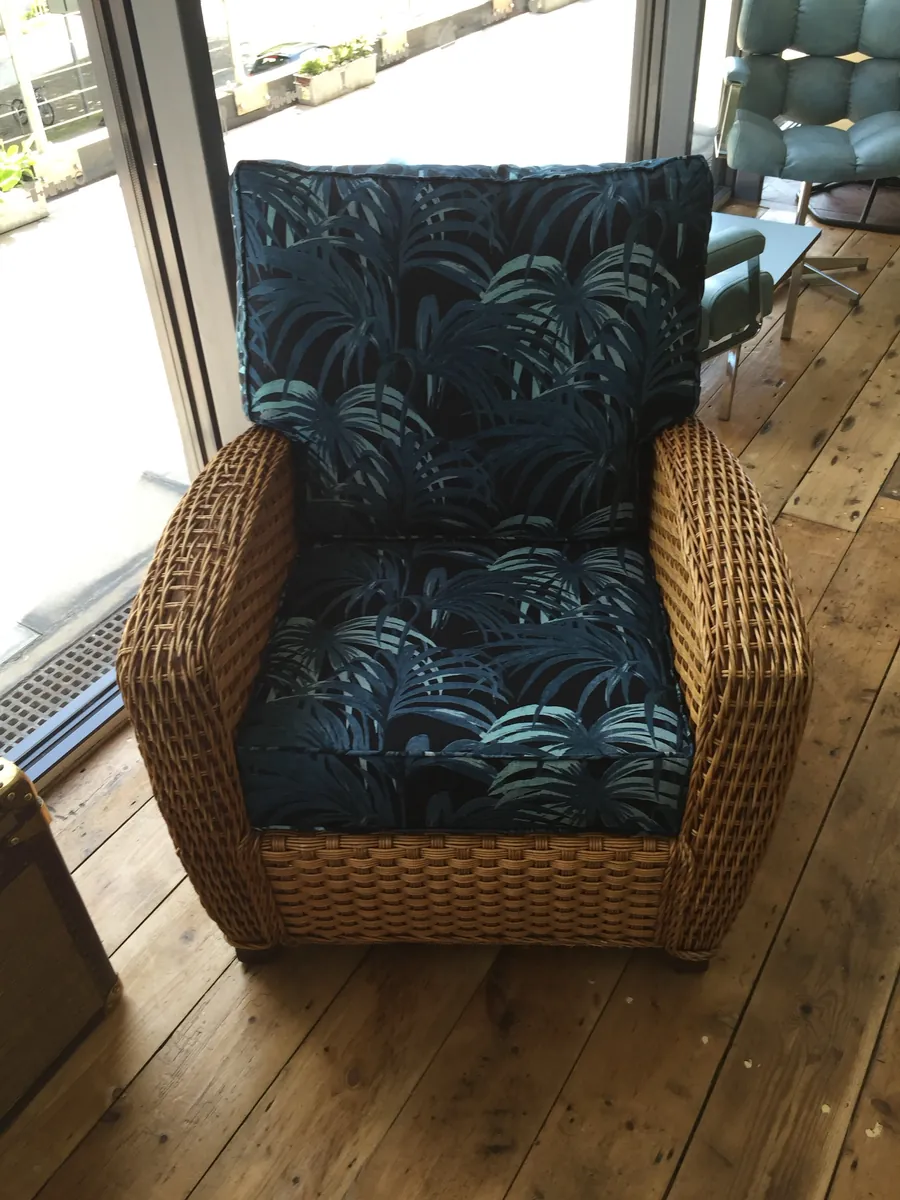 A chunky wicker armchair with navy palm-print cushions
